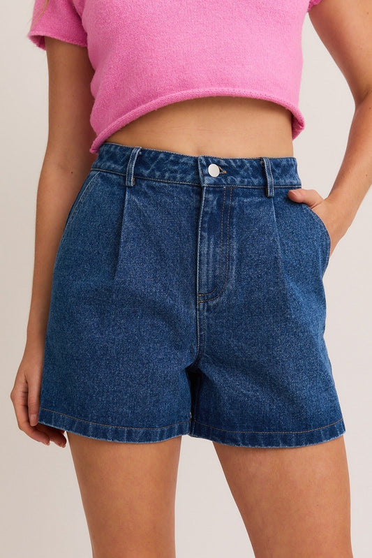 A dark wash high-rise short with a front pleat and clean hem